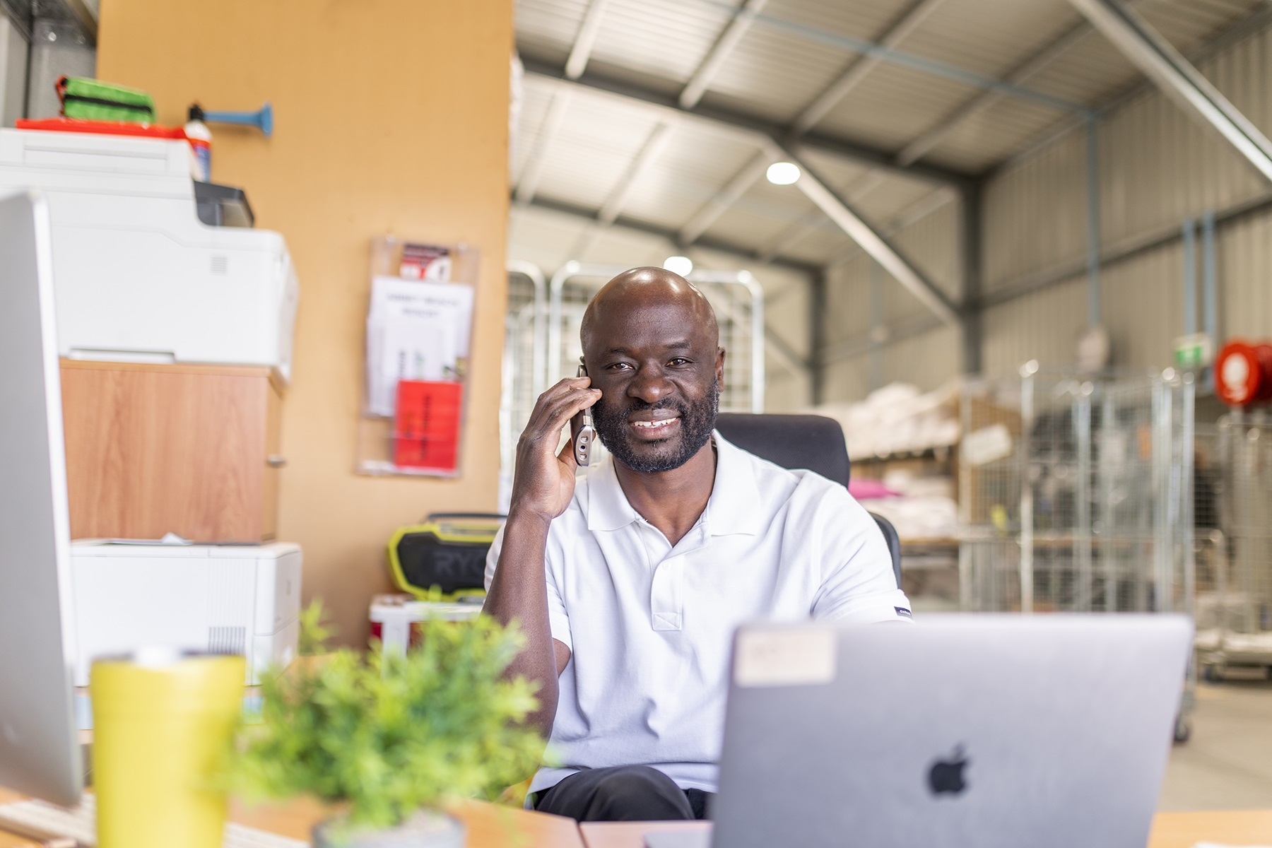 Photo of Ezekial Amudala on the phone in his business Baythe Linen and Laundry.