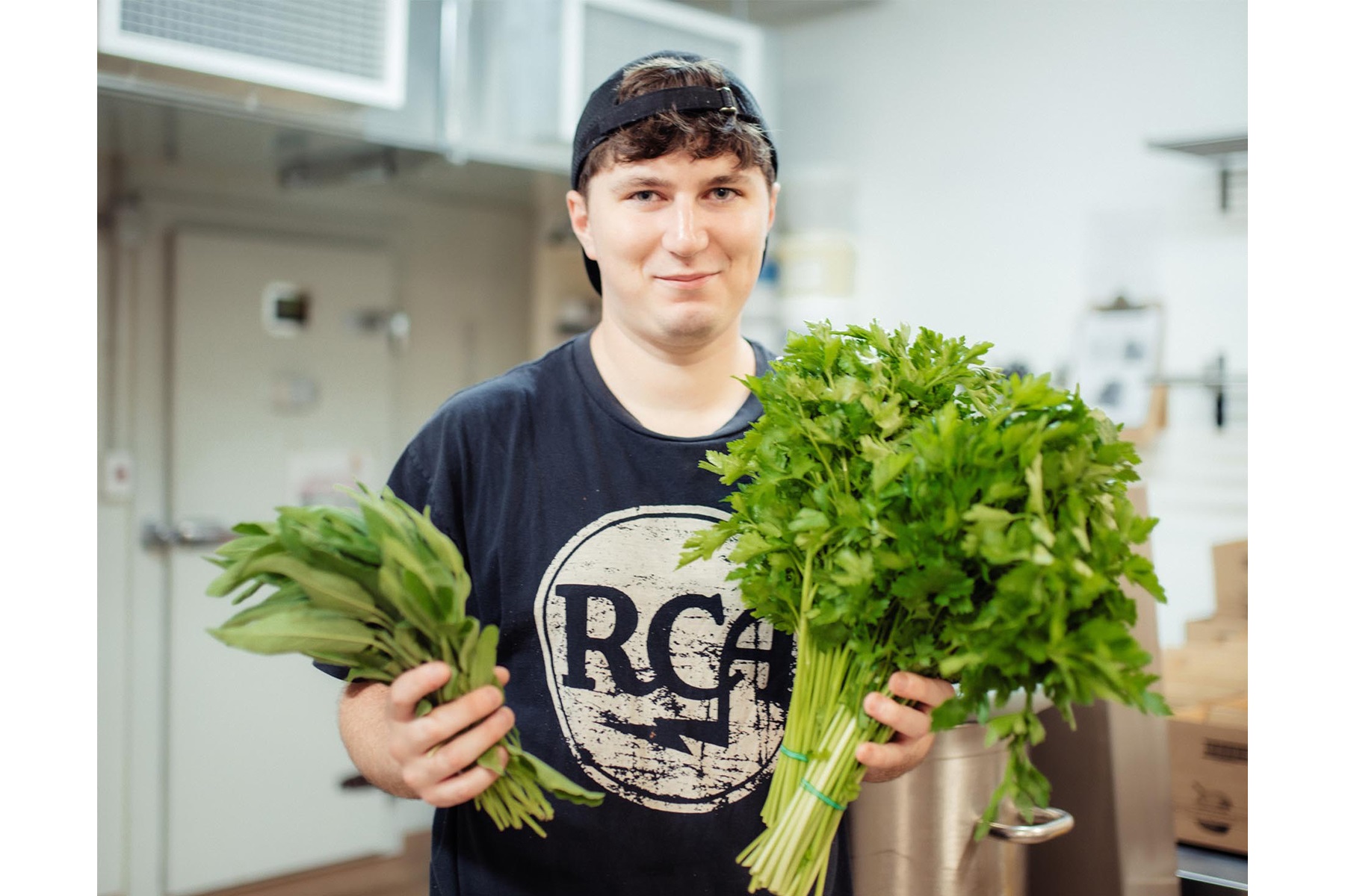 Photo of Urban Forager employee Jack Benwell holding produce in the business's production kitchen.