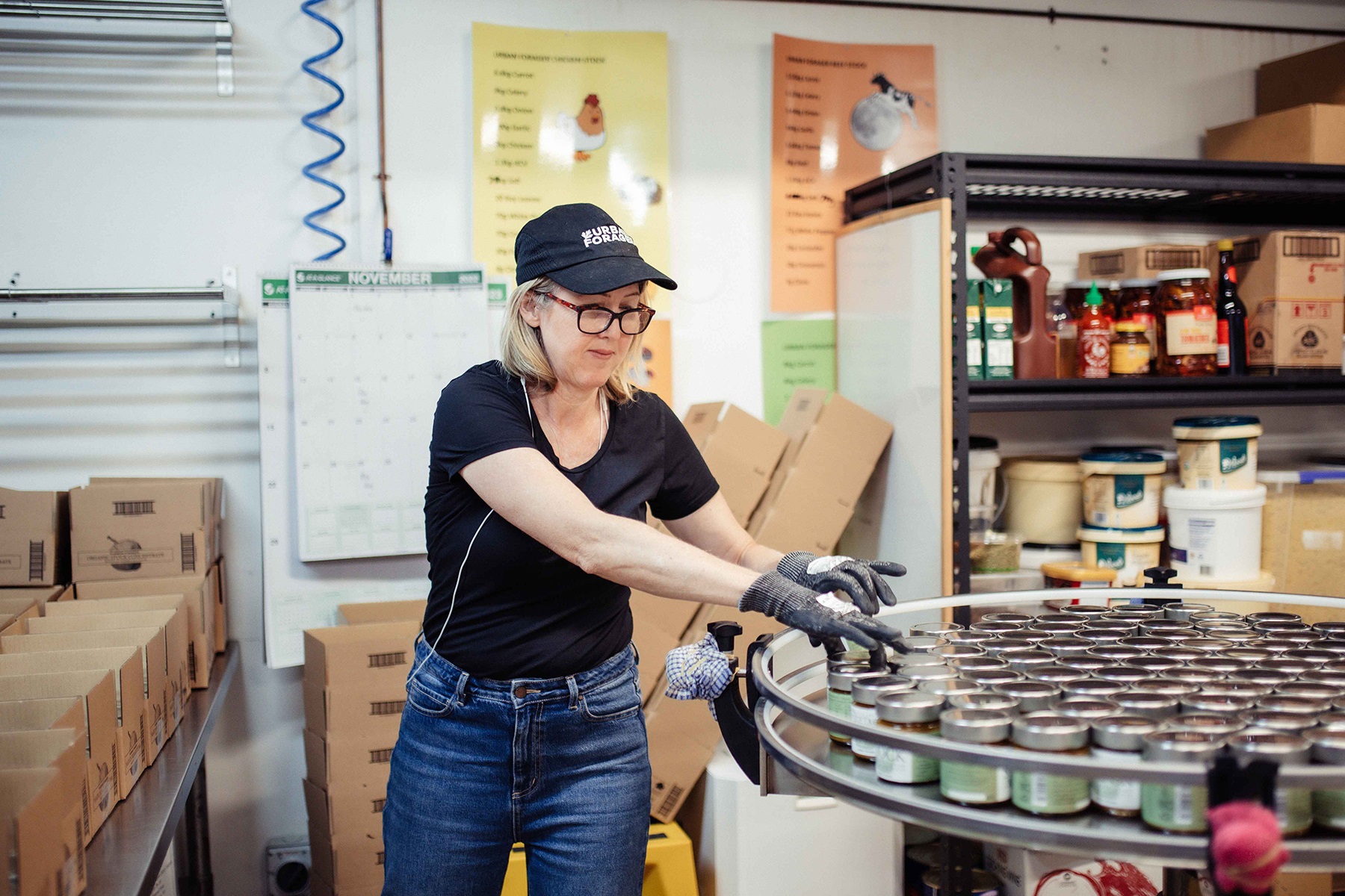 Photo of Lou Courteen, owner of Urban Forager, handling bottled products in her commercial kitchen.