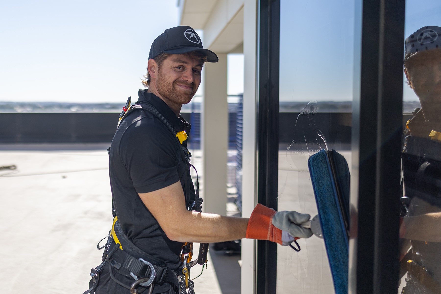 Photo of Alex Butchart, owner of High Access Window Cleaning, cleaning a window.