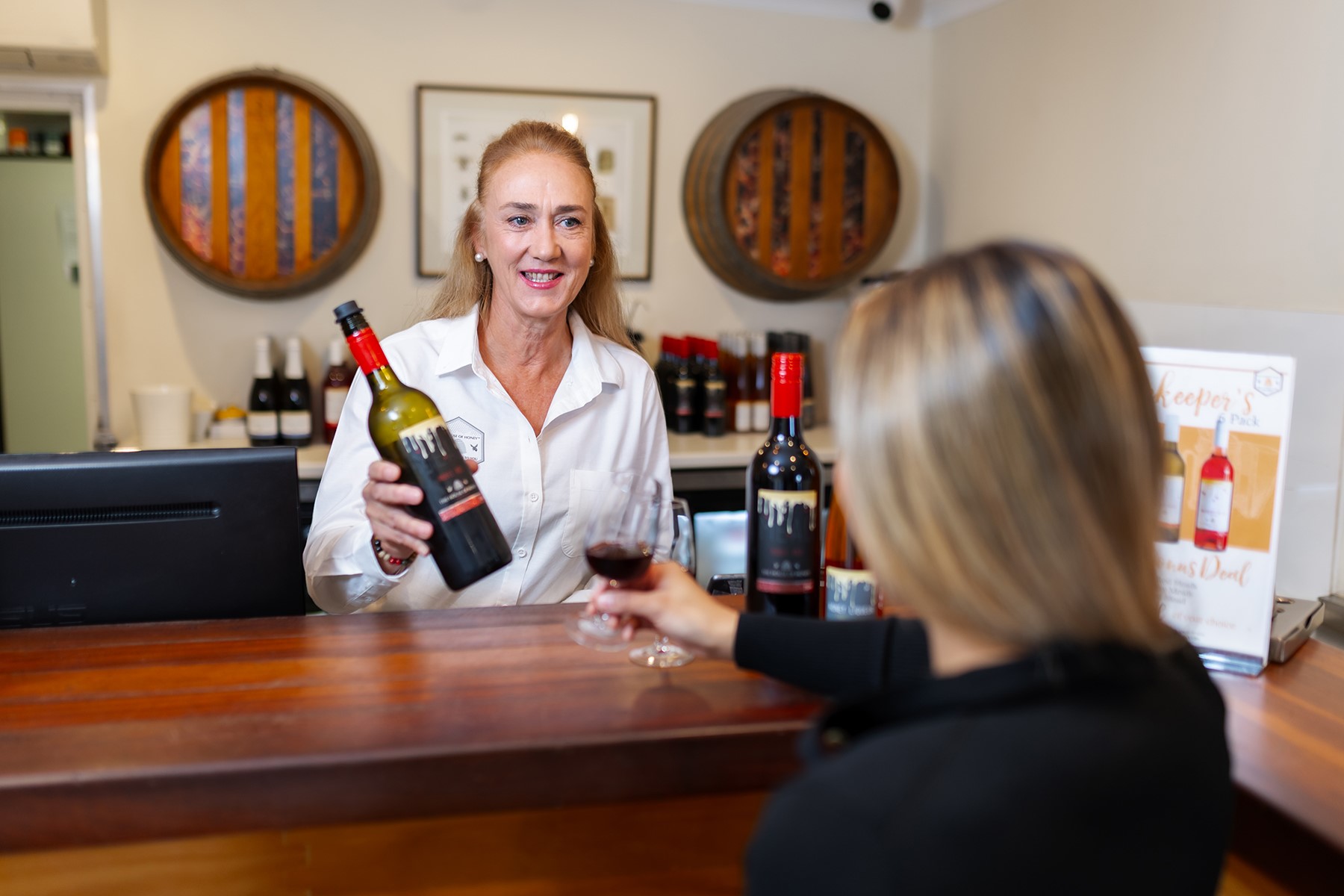 Photo of Kim Phillips, co-owner of The House of Honey, pouring a glass of mead to a customer.