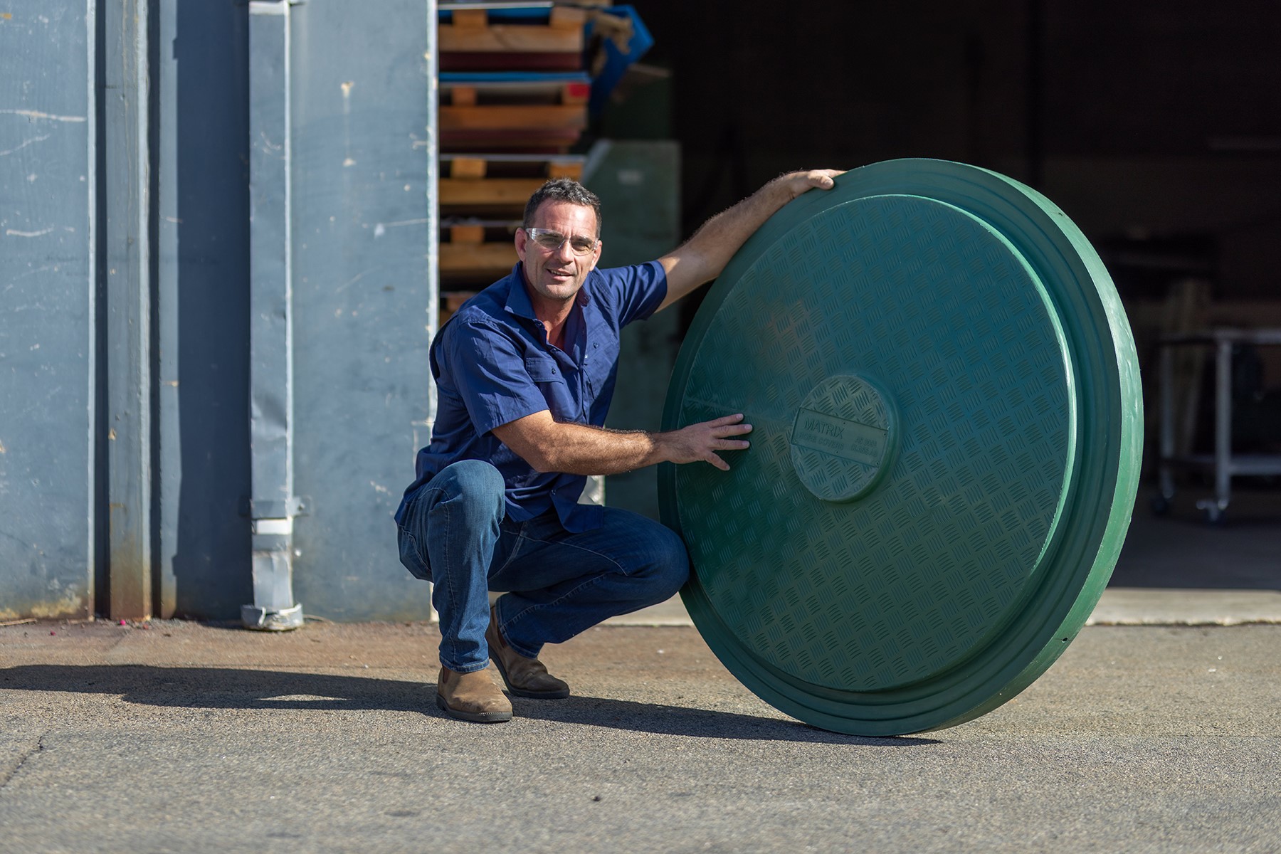 Photo of Ben Kraucevs, owner of Matrix Bore Covers. He is crouched next to one of his bore covers.