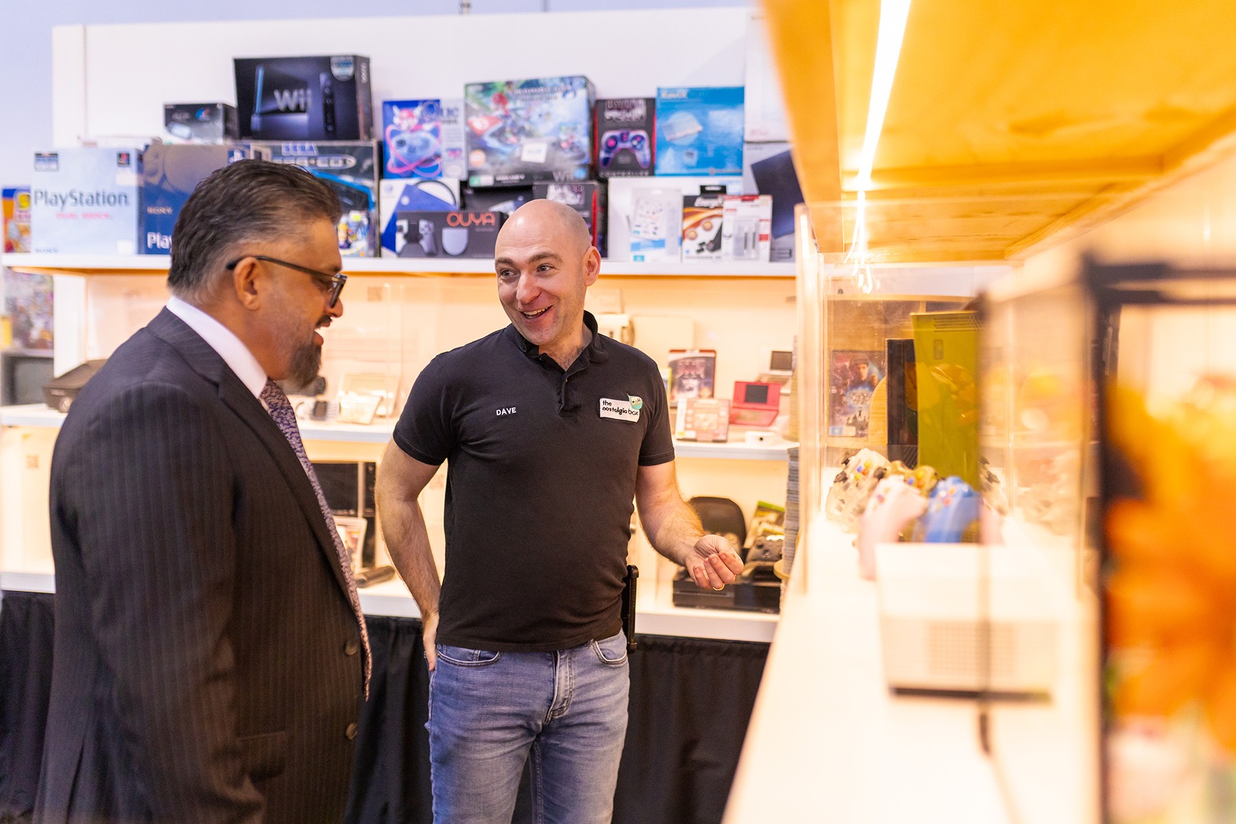 David Green, owner of The Nostalgia Box, showing WA Small Business Commissioner Saj Abdoolakhan the retro consoles on display in his business. 