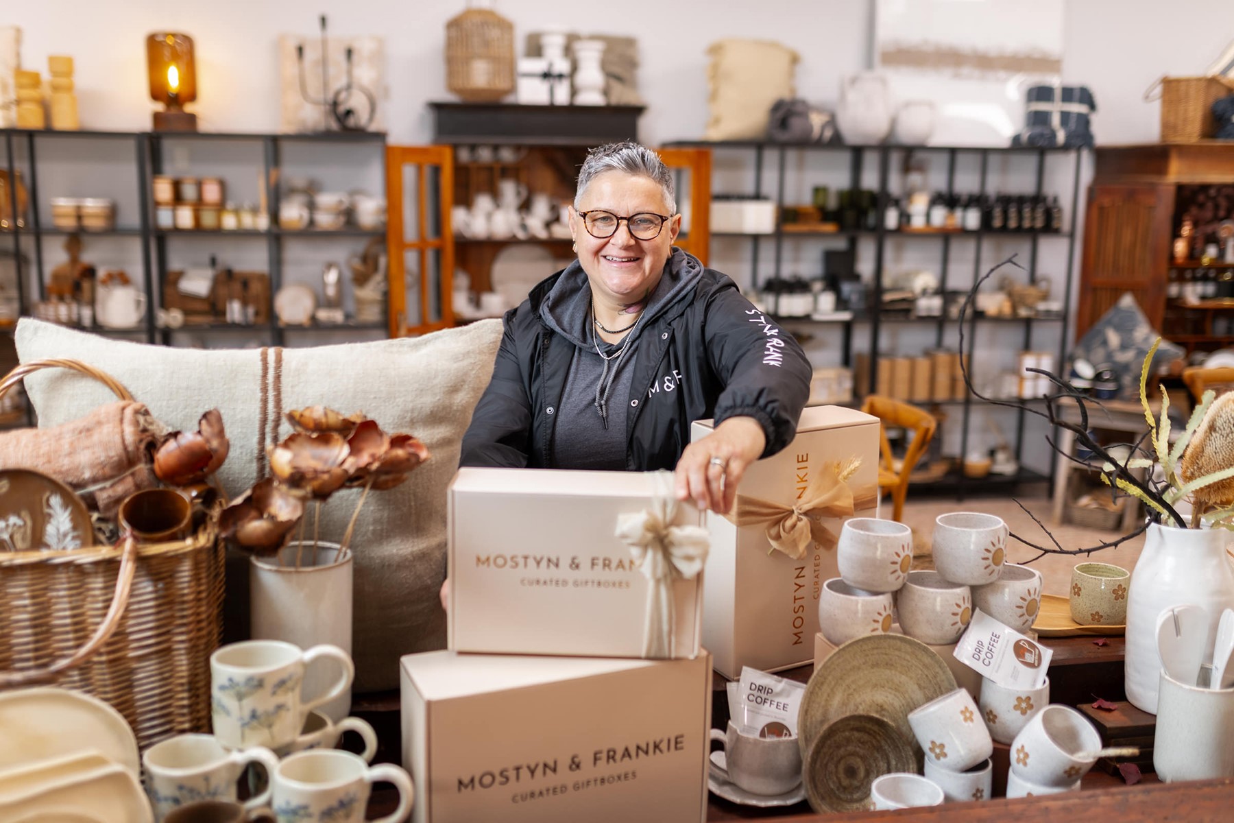 Photo of Frankie Holden, co-owner of Mostyn & Frankie Curated Giftboxes, standing in her retail store.