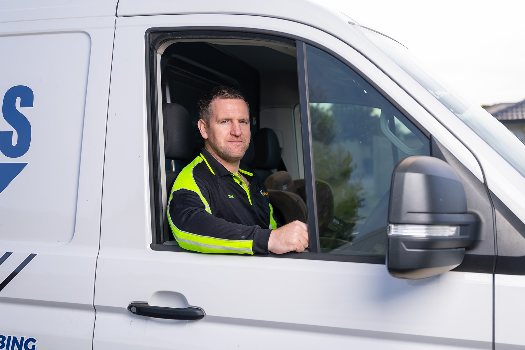 Photo of a male tradesperson sitting in a work van.