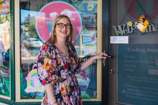 A woman standing at the entrance of her retail store.