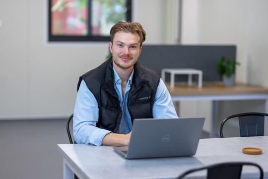 Dane Cocliff, owner of I2R Modular, sitting at a table with a laptop in front of him.