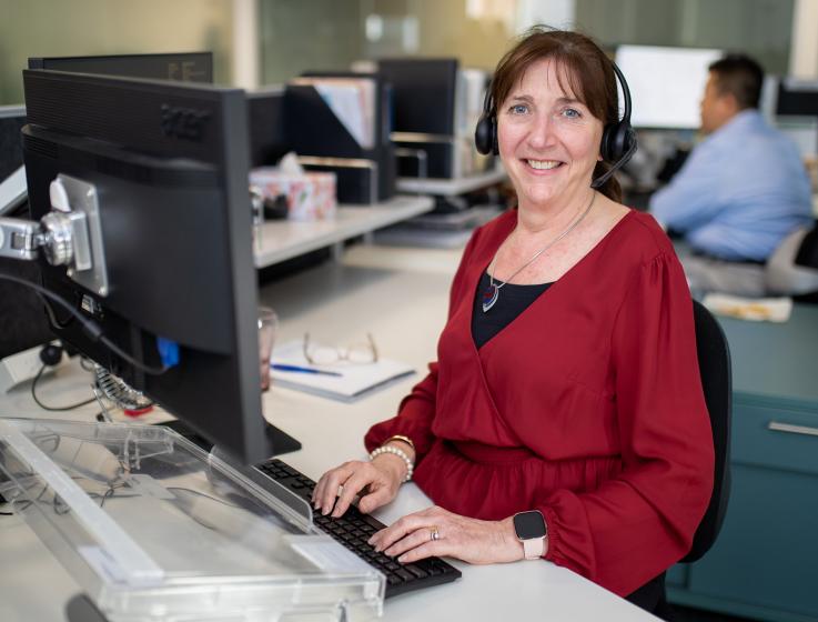 Photo of a female member of staff at the SBDC working at her computer and wearing a telephone headset.