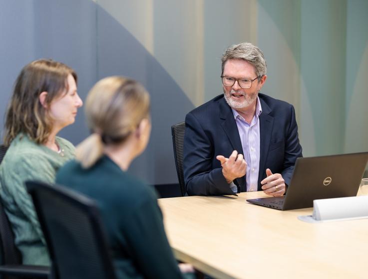 Photo of a male SBDC staff member providing advice to two female clients..