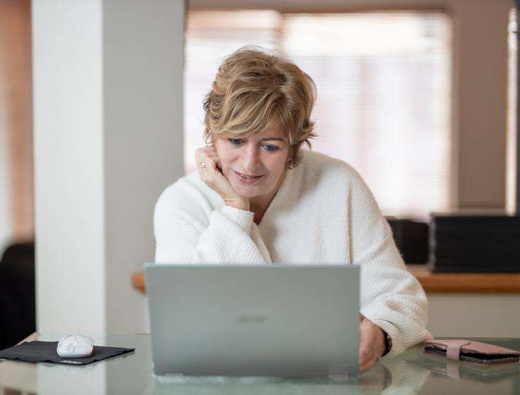 Photo of a female business owner reading from a laptop.