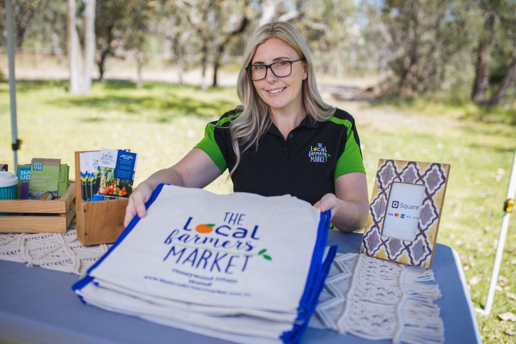 Image of a woman sitting behind a market stall smiling at the camera