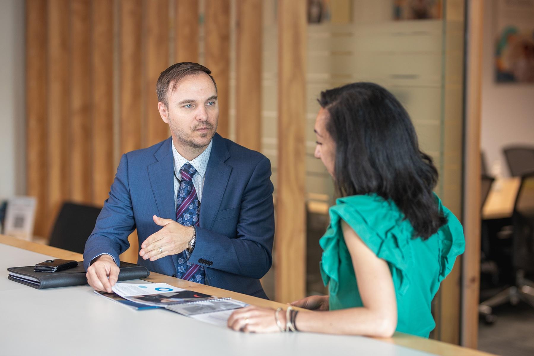 A photo of a male and female SBDC employees having a work meeting where they are reviewing documents.