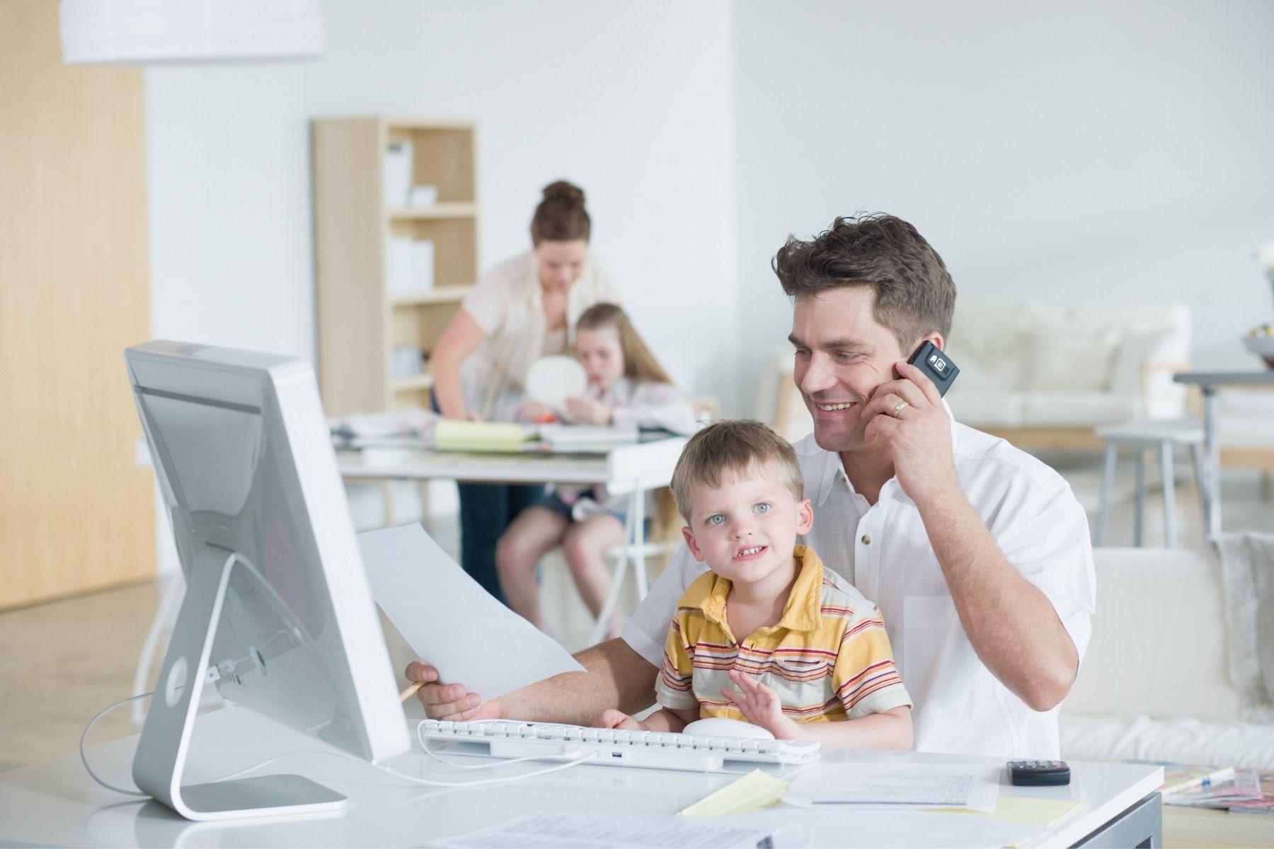 Photo of a couple working from home with their children.