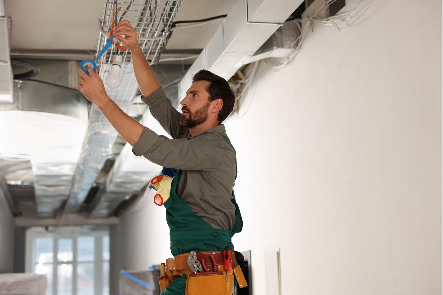 A male tradesman repairing a light in a building.