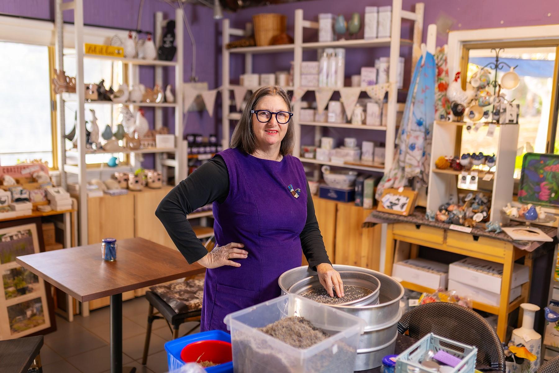 Photo of a woman standing in her retail shop. She is sifting lavender through a sieve.