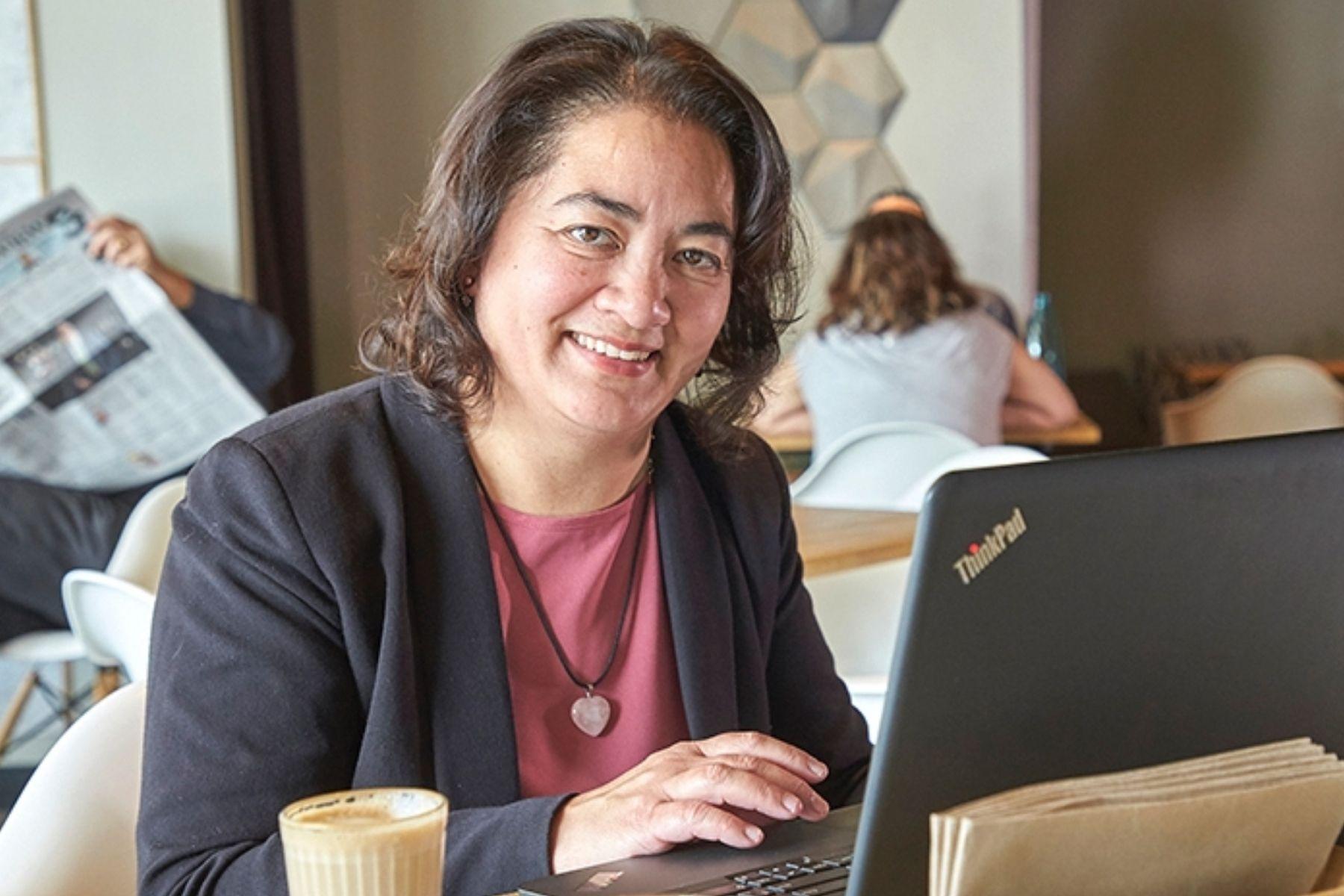 Photo of a woman in a cafe working on a laptop.