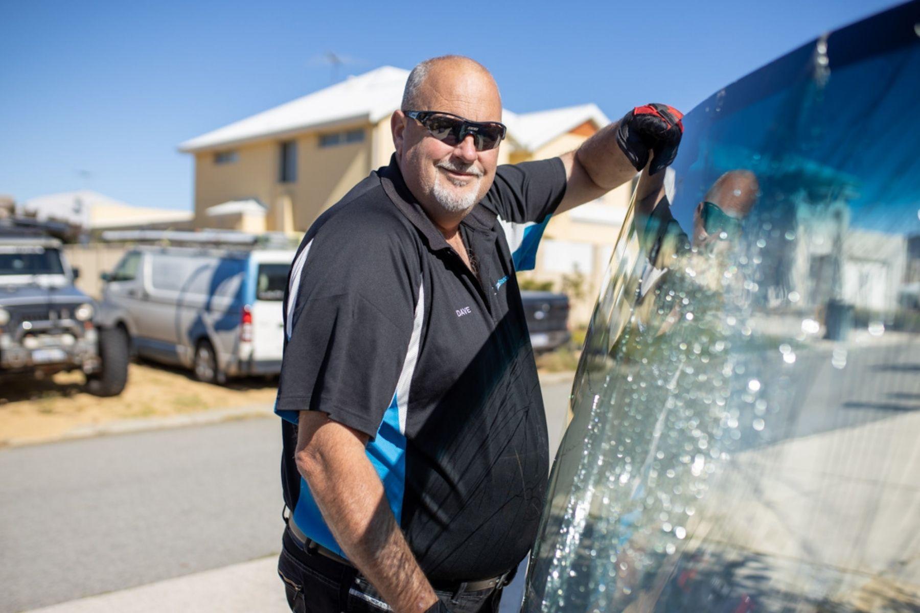 Image of a man standing holding a large shattered pane of glass