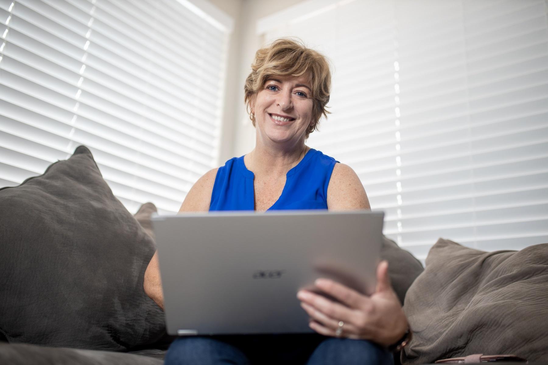 A woman sitting on a couch while using a laptop.