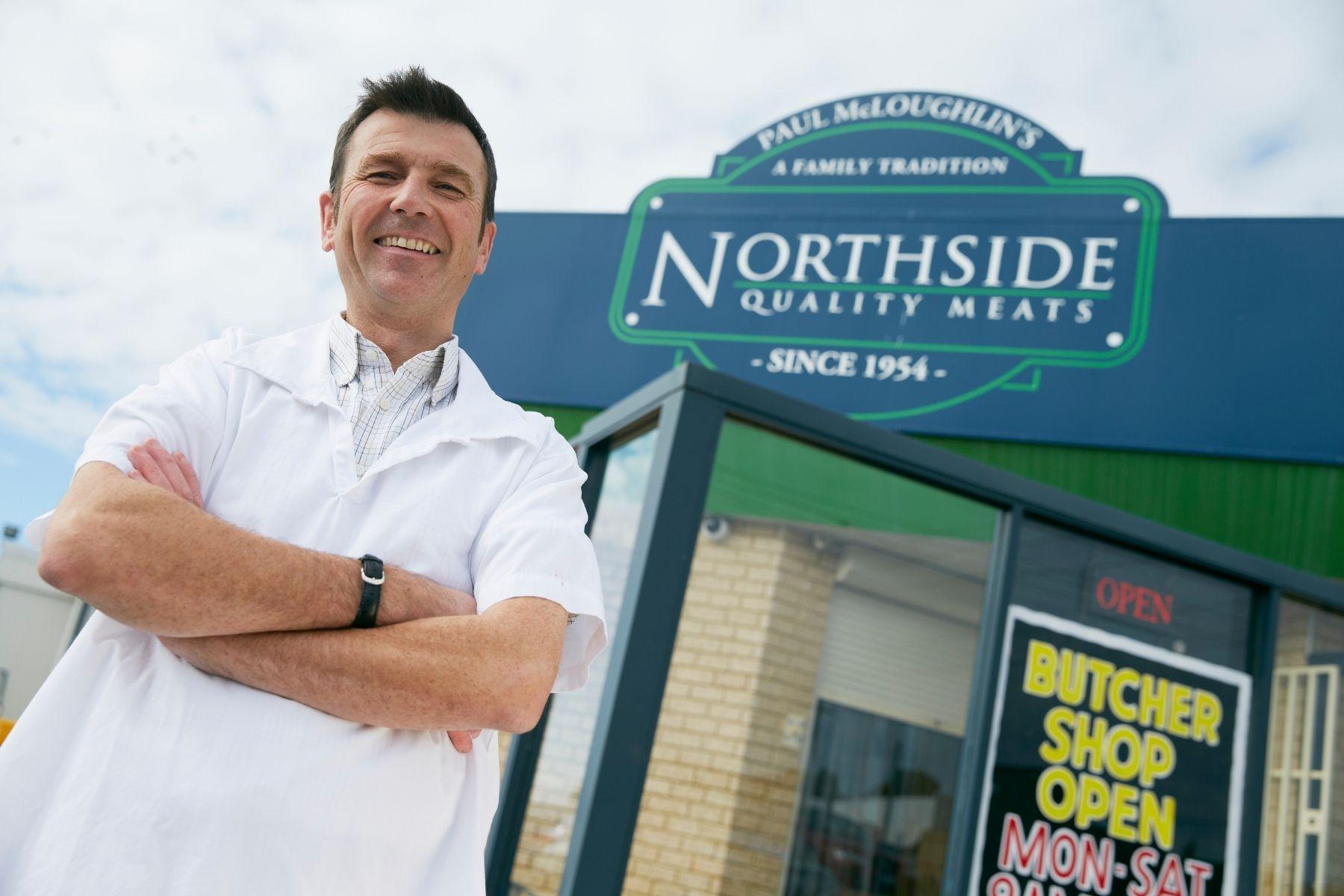 Photo of a butcher outside of his store.