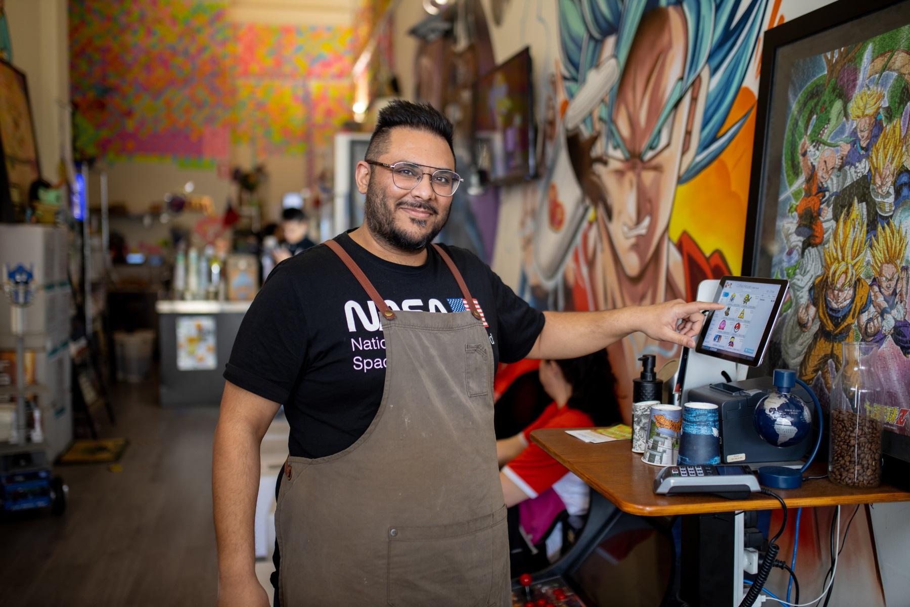 Photo of a cafe owner using a point of sale terminal.