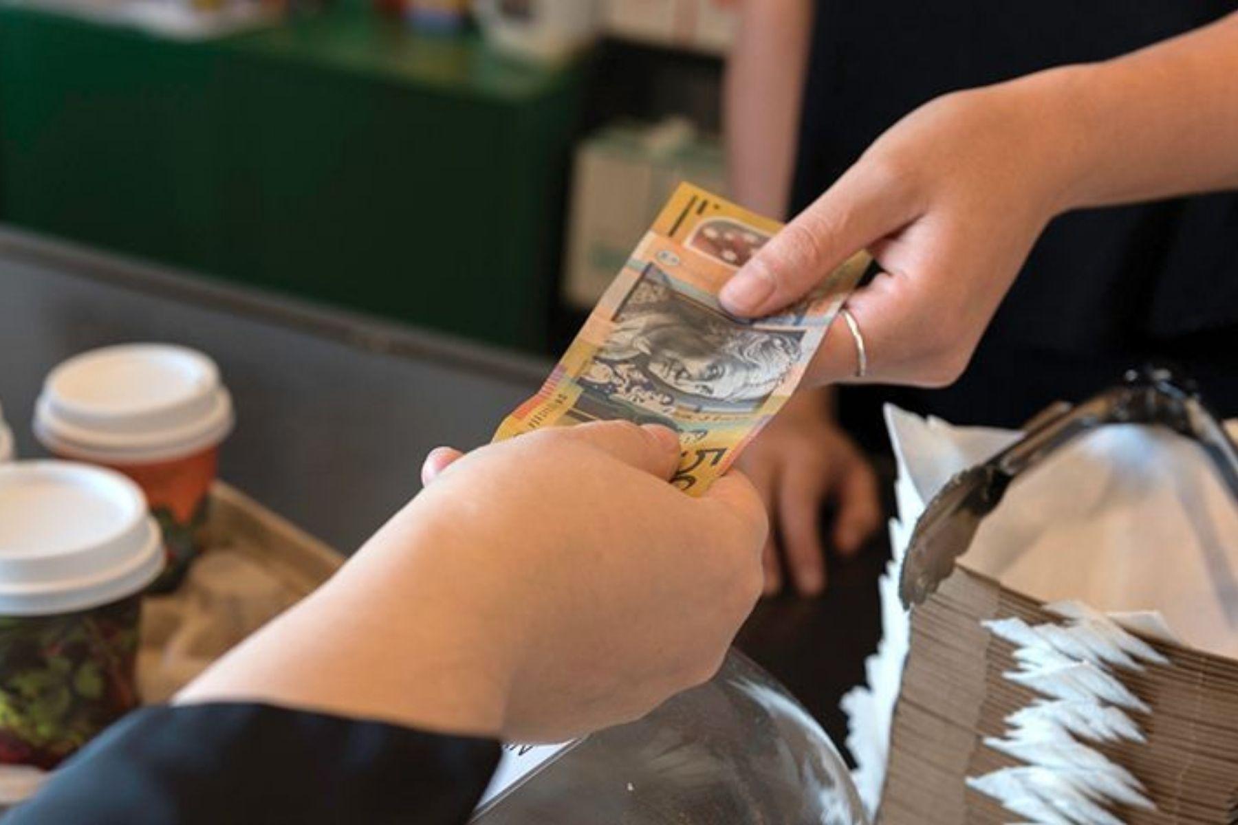 Photo of a customer handing over a $50 note to a cafe worker.