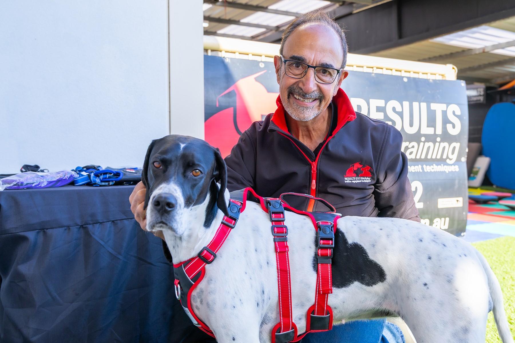 Photo of Orlando dos Santos, owner of Results Dog Training. He is pictured with a dog and is smiling at the camera.