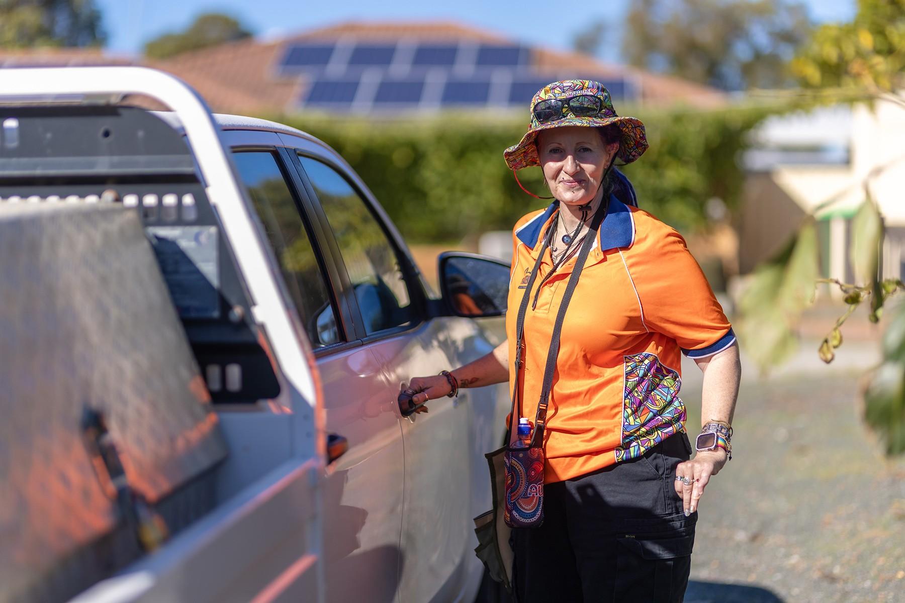 Jakki Kruger, owner of Serene Earth Sustainability, standing at the driver's side door of her work ute.