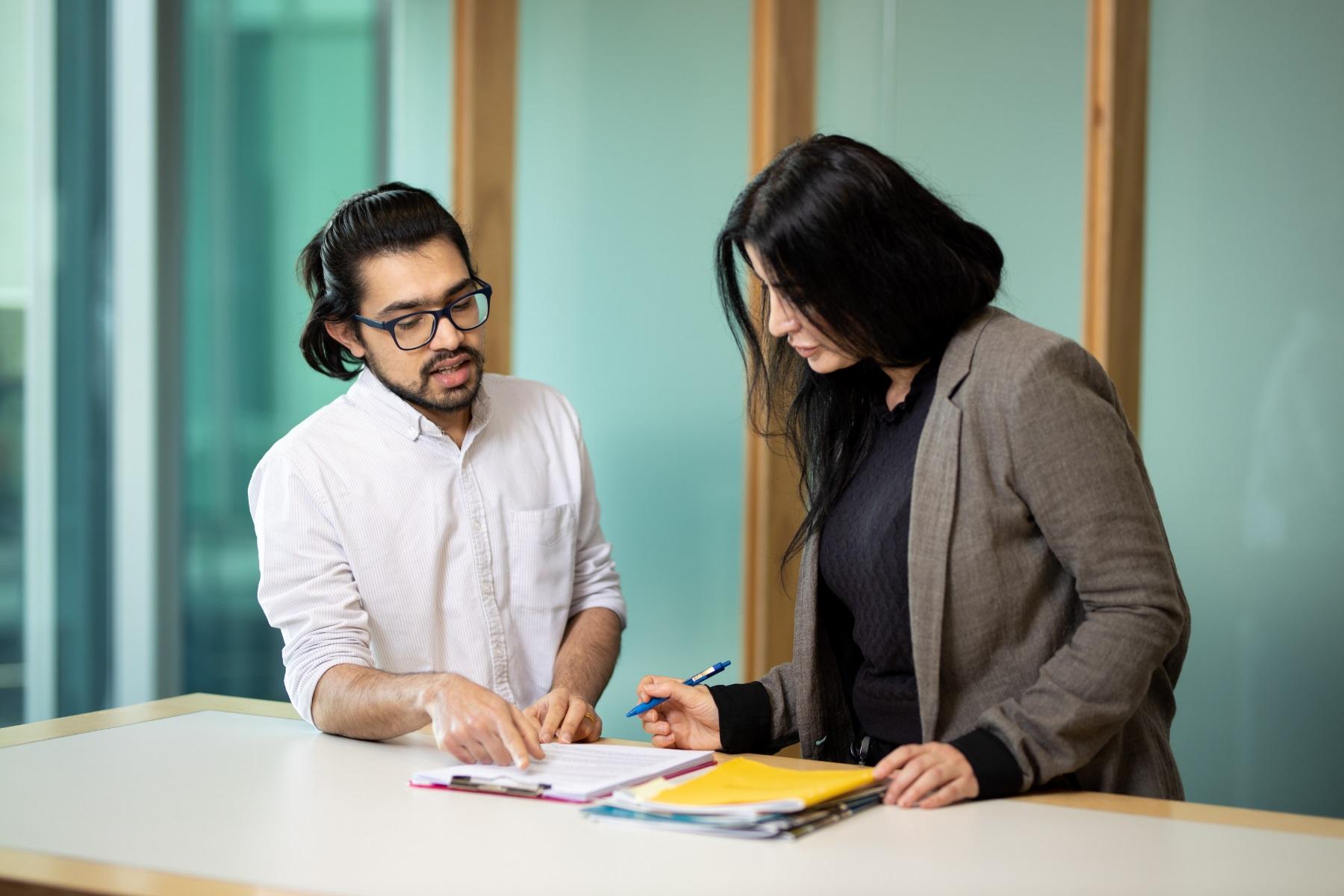 Woman and man standing over a high table looking at paperwork.