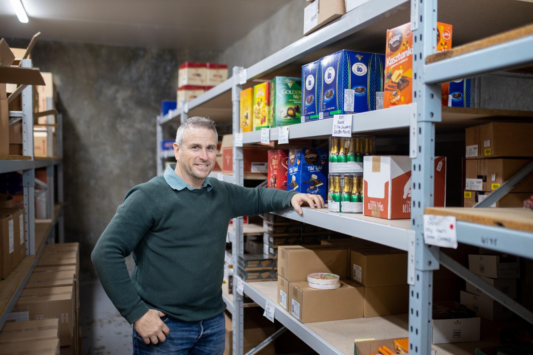 Image of a man standing in front of shelves in a warehouse.