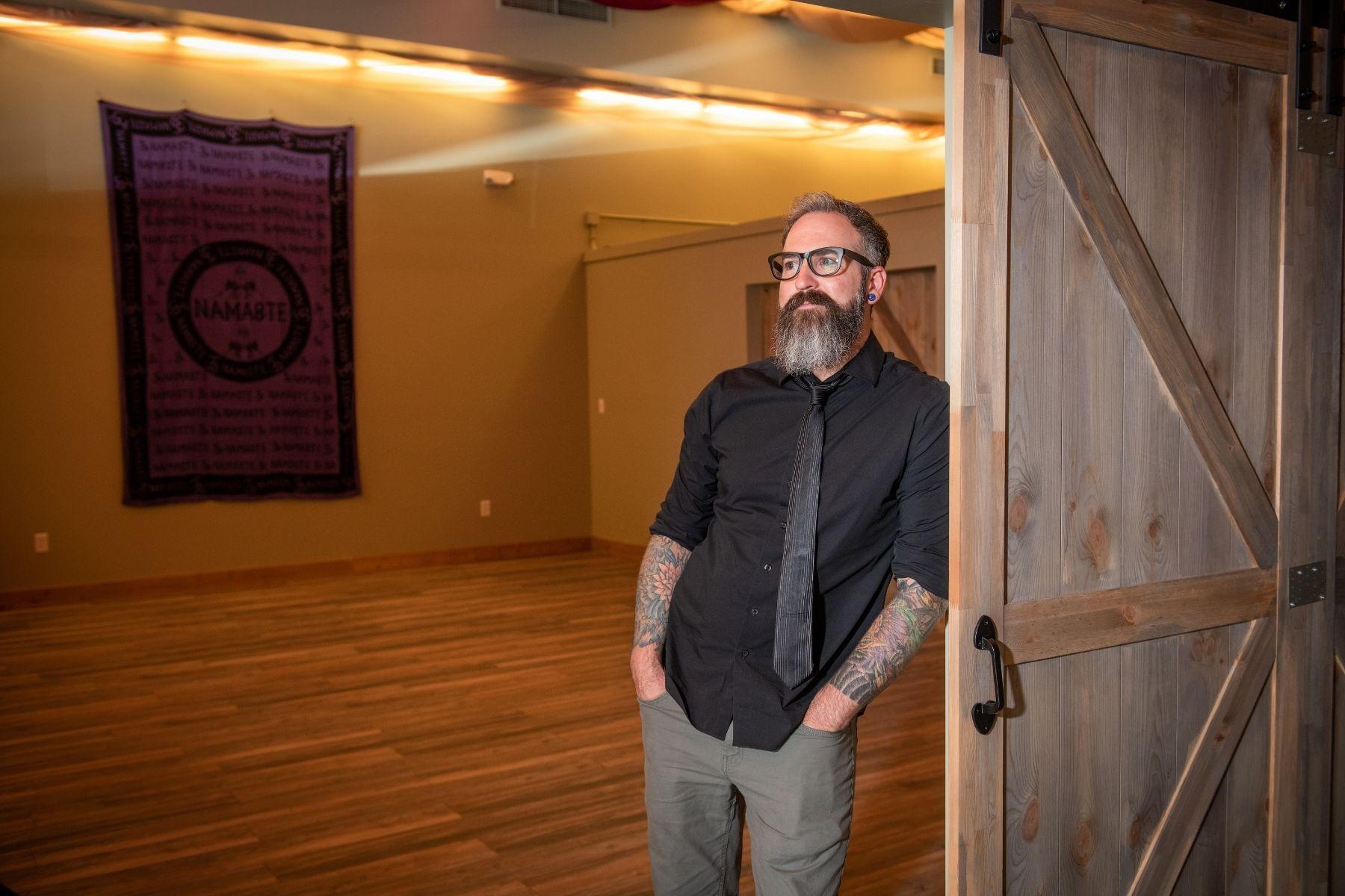Photo of a man leaning against a door.