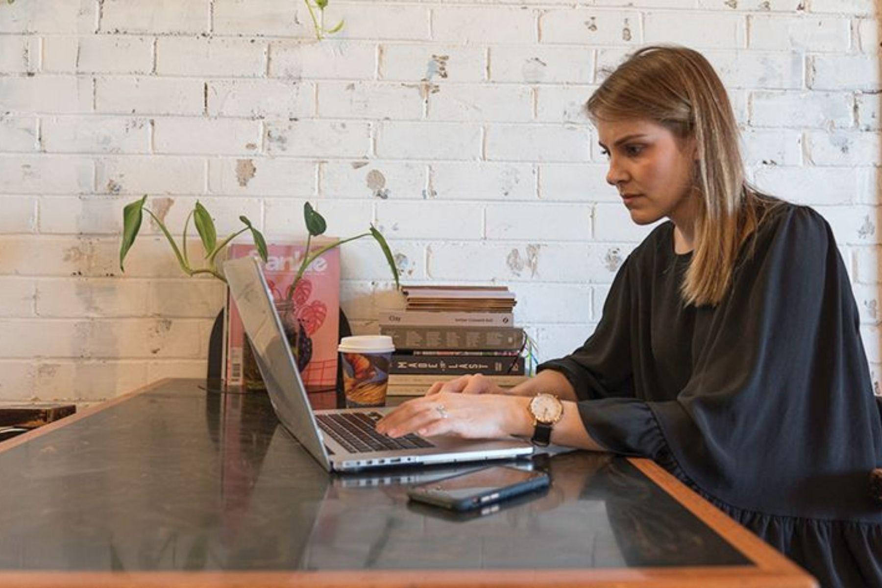 Photo of a woman working on a laptop in a cafe.