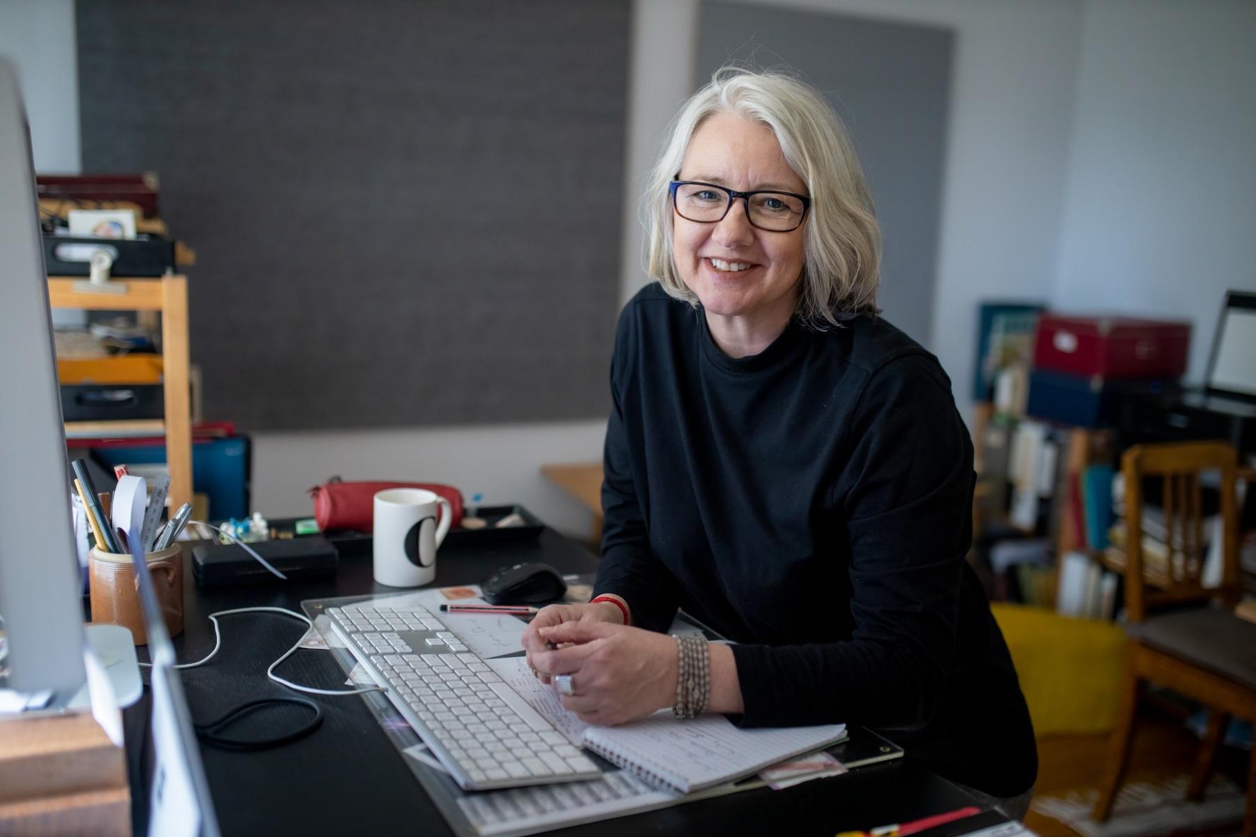 Photo of a woman in a home office smiling at the camera.