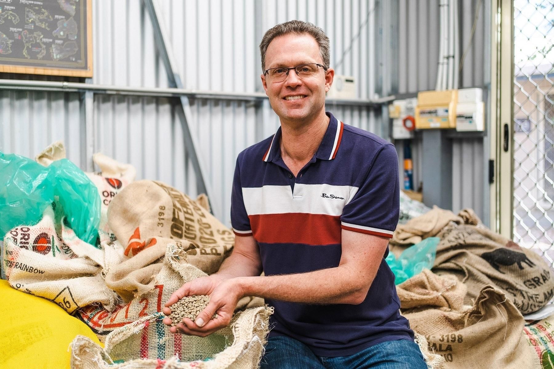 Photo of Kade Sims, owner of Beck & Call Coffee in Albany. He is holding coffee beans in his hands.