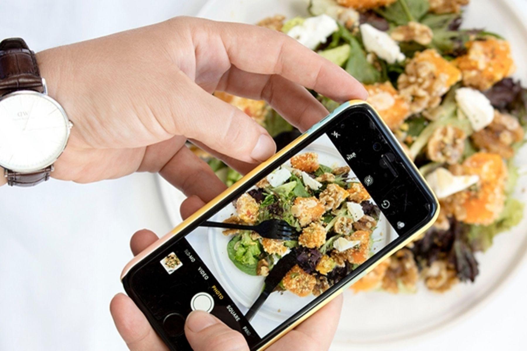Photo of  a person using their smartphone to take a photo of their meal.