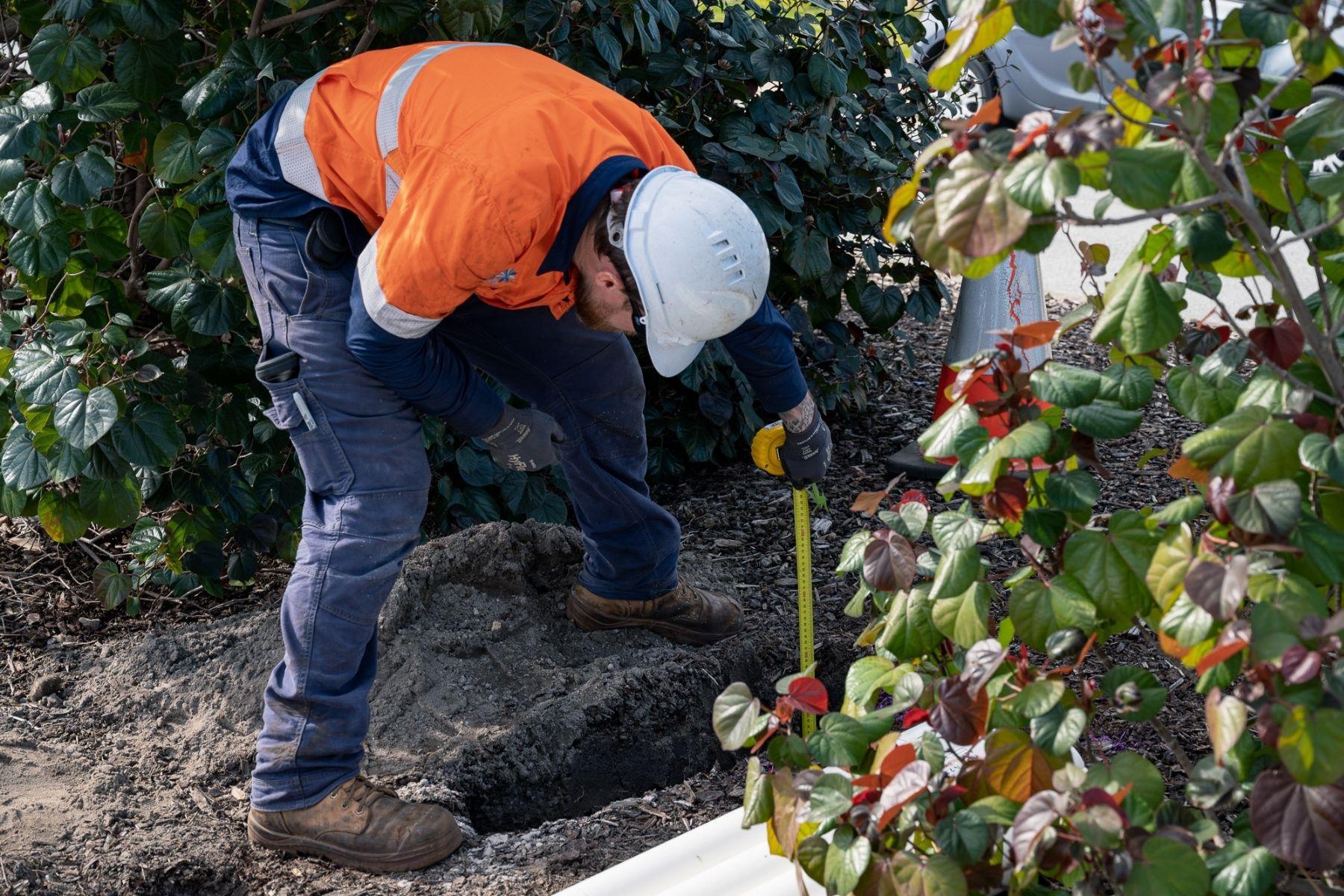 Photo of a tradie measuring a hole.