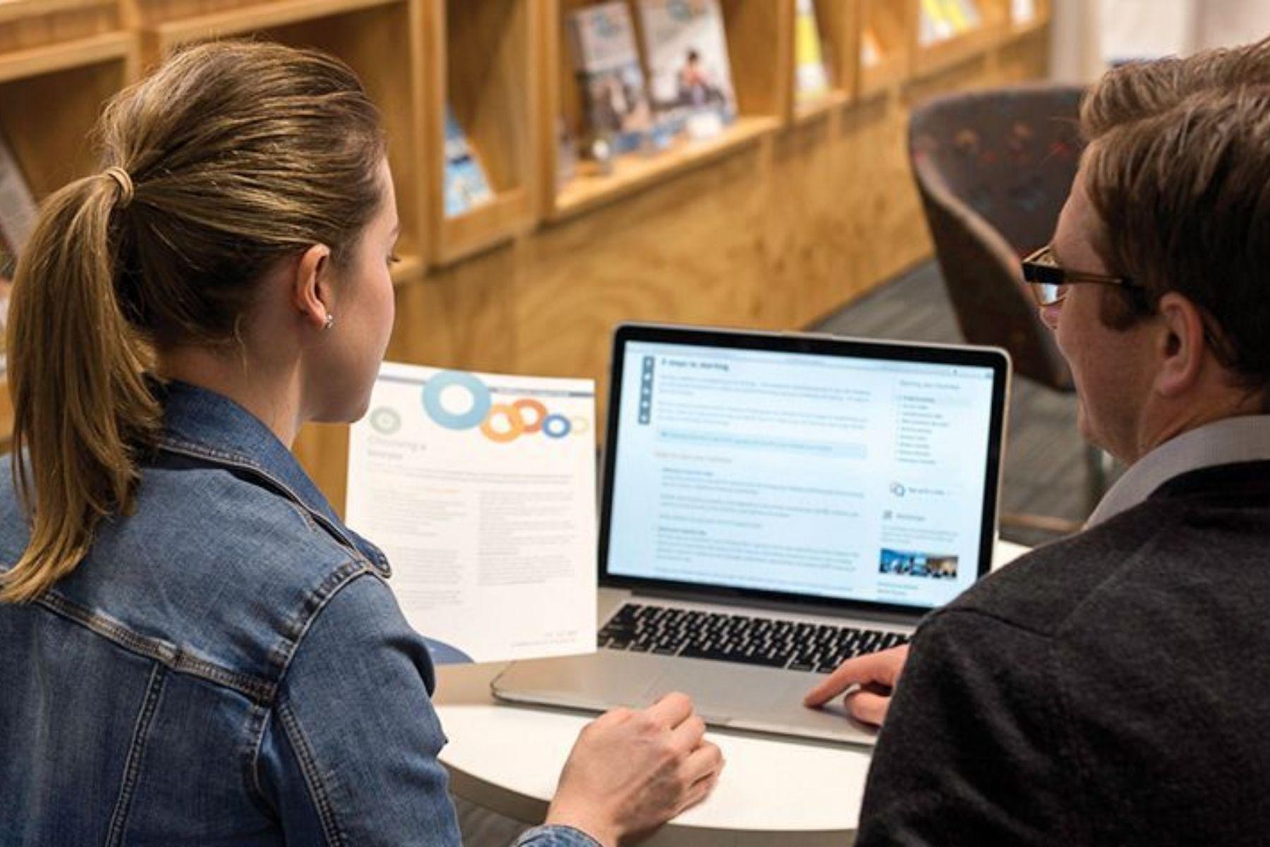Photo of an SBDC business adviser and a client reviewing information on a laptop.