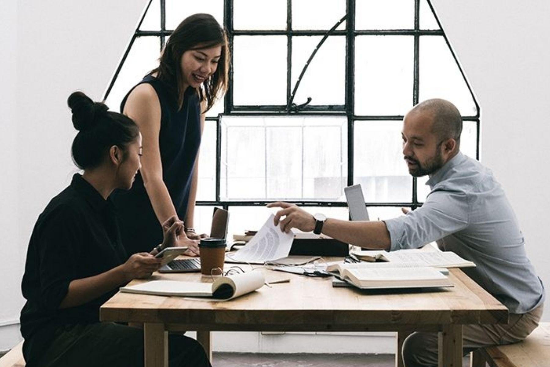 Photo of two women and a man reviewing documents at a table.