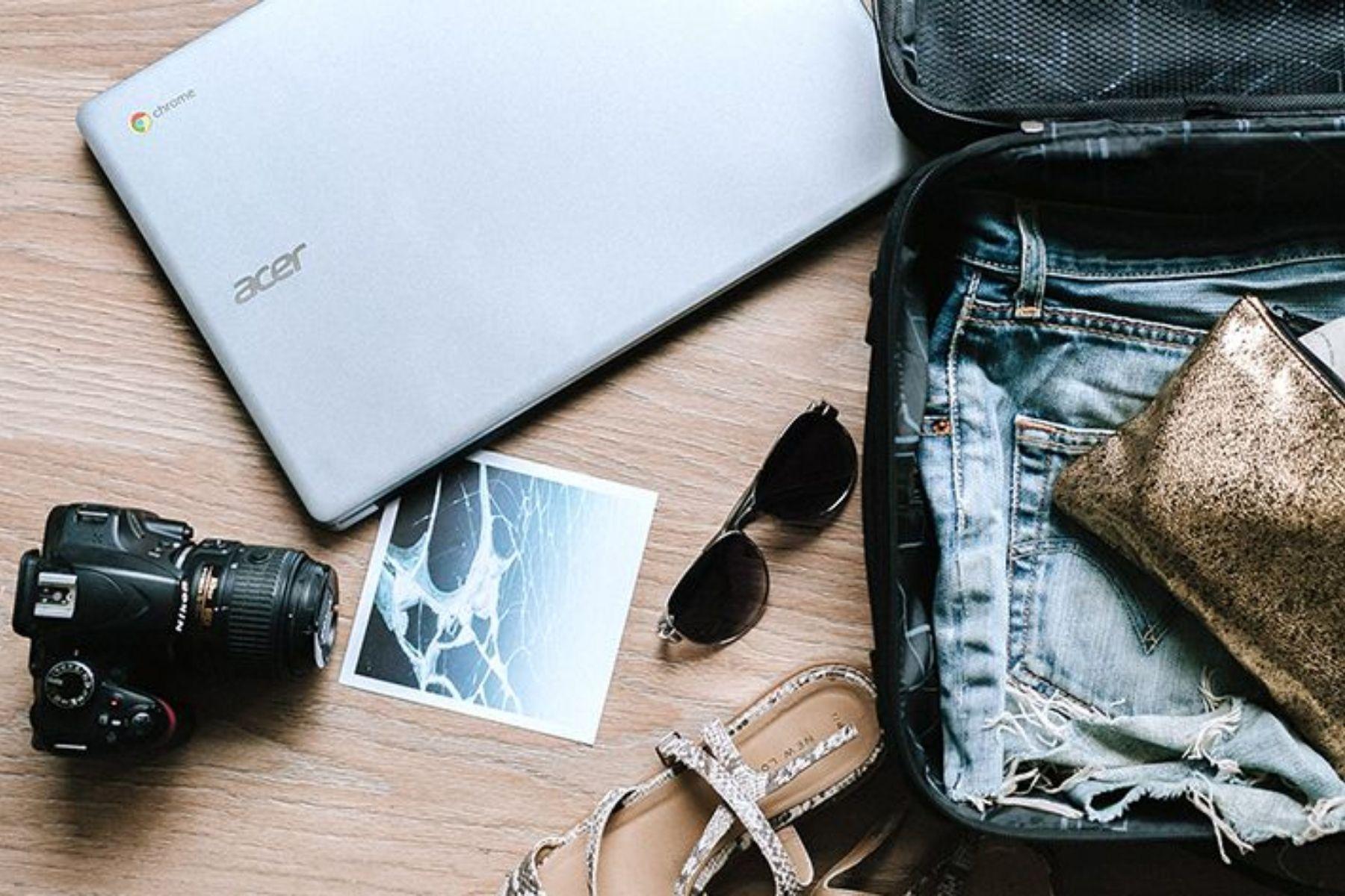 Photo of a packed suitcase, laptop, camera and sunglasses.