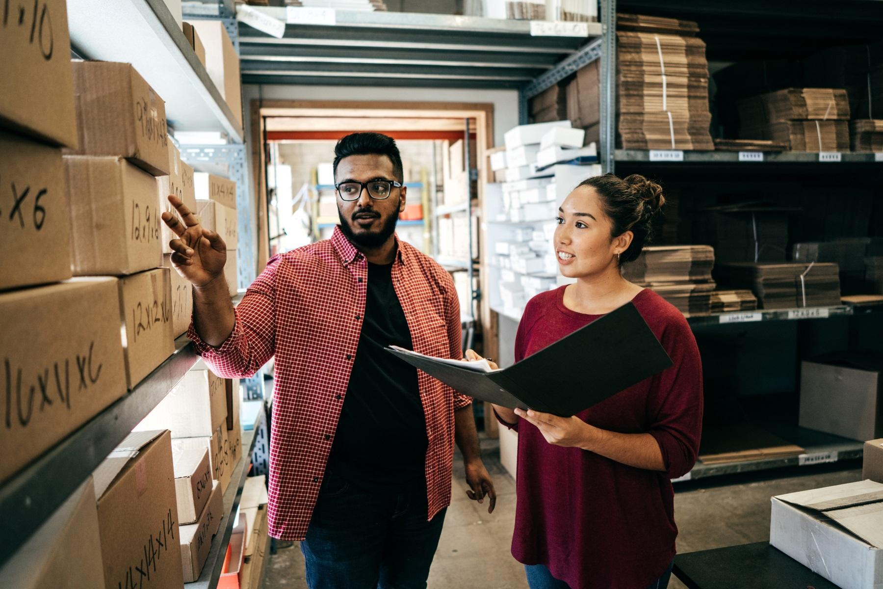 Photo of a man and woman conducting a stocktake in their business warehouse.