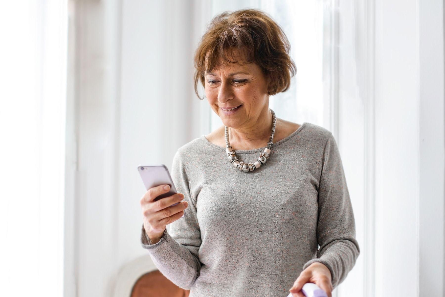 Photo of a mature aged woman browsing on a smart phone.
