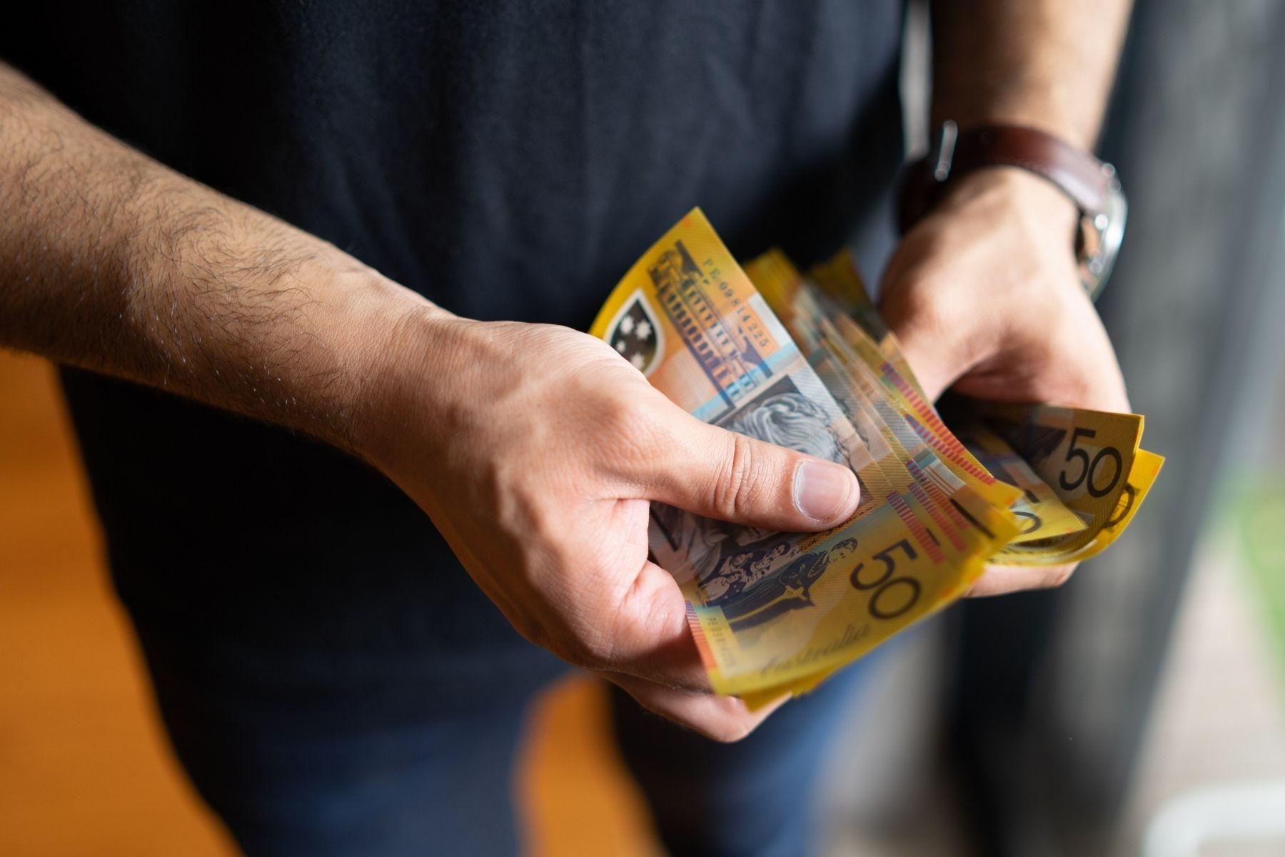 Photo of hands counting $50 notes.