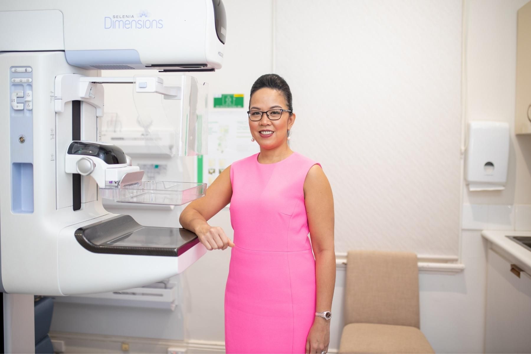A photo of a woman next to an xray screening machine.