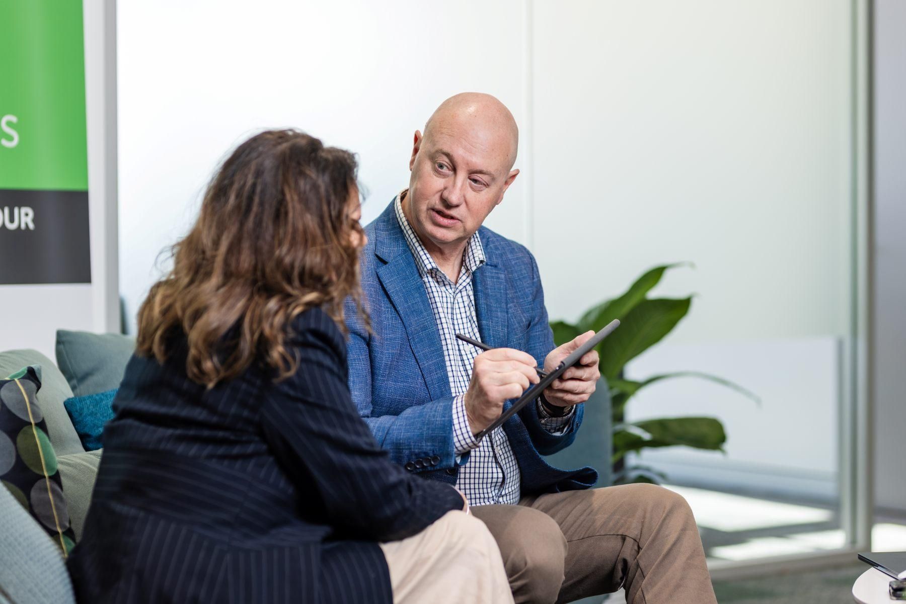 A male business owner meets with a female staff member in a casual seated setting
