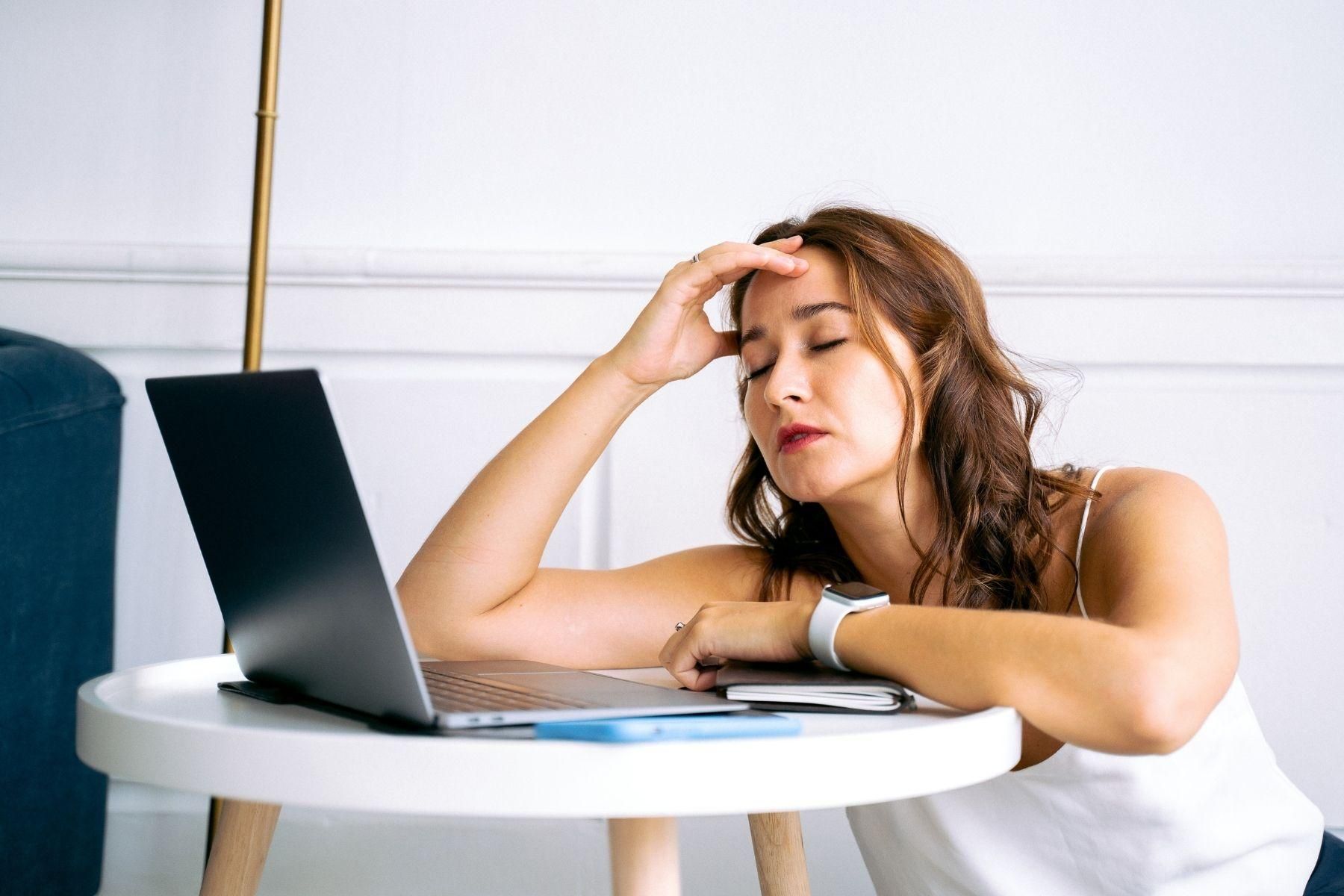 Photo of a female business owner looking stressed out in front of a laptop.