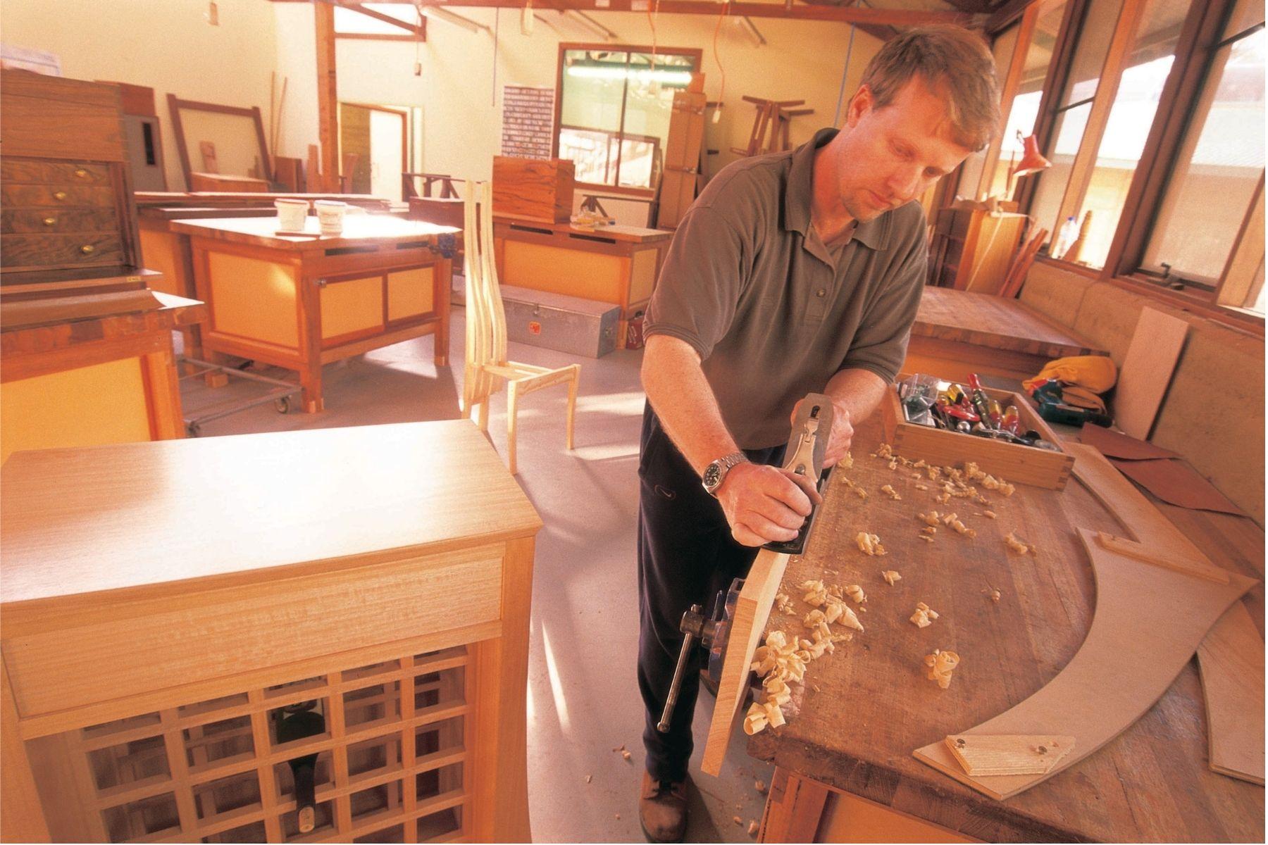 Photo of a woodworker using a hand plane to square up a piece of wood.