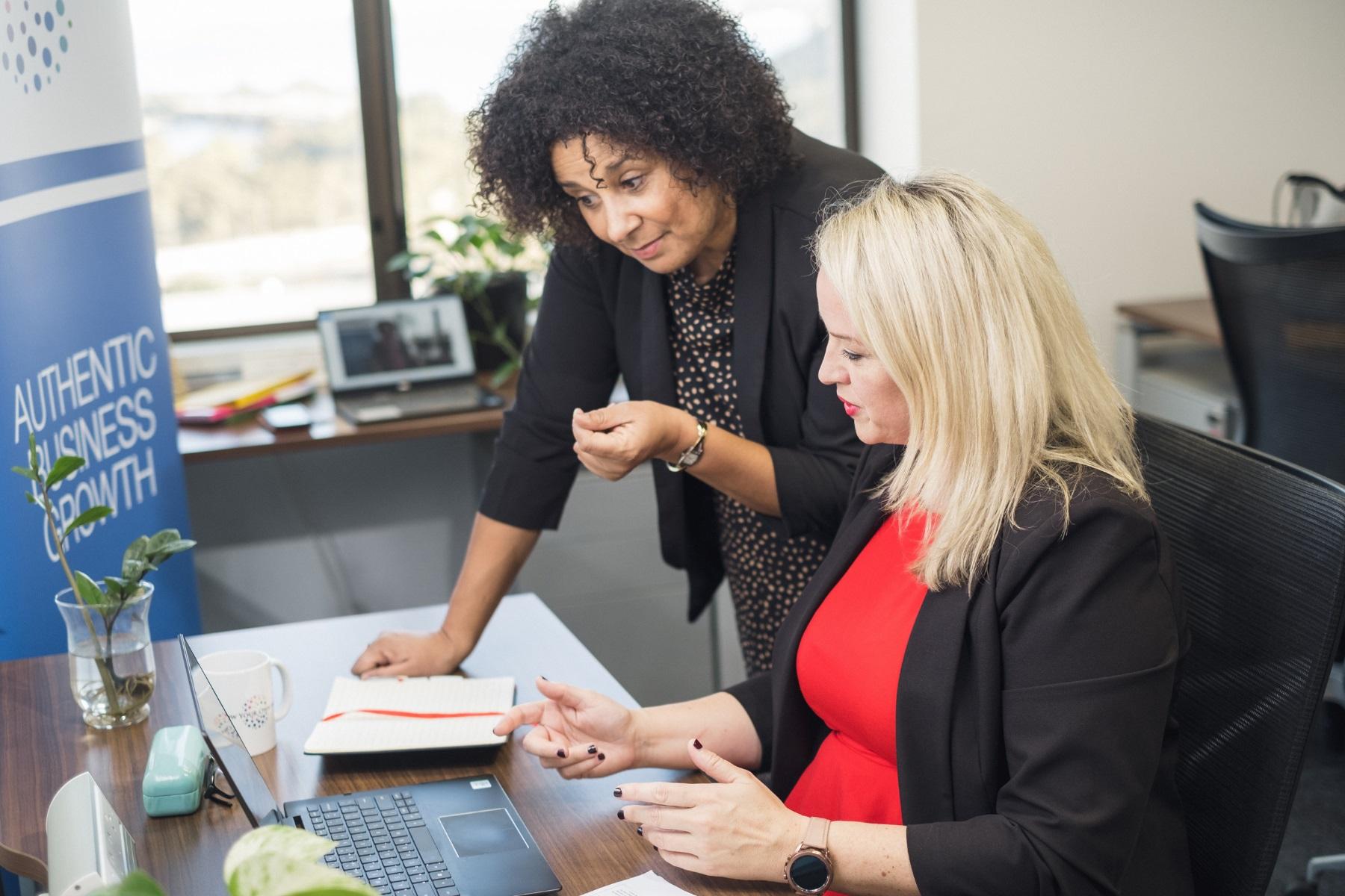 Photo of two female business partners reviewing information on a laptop.