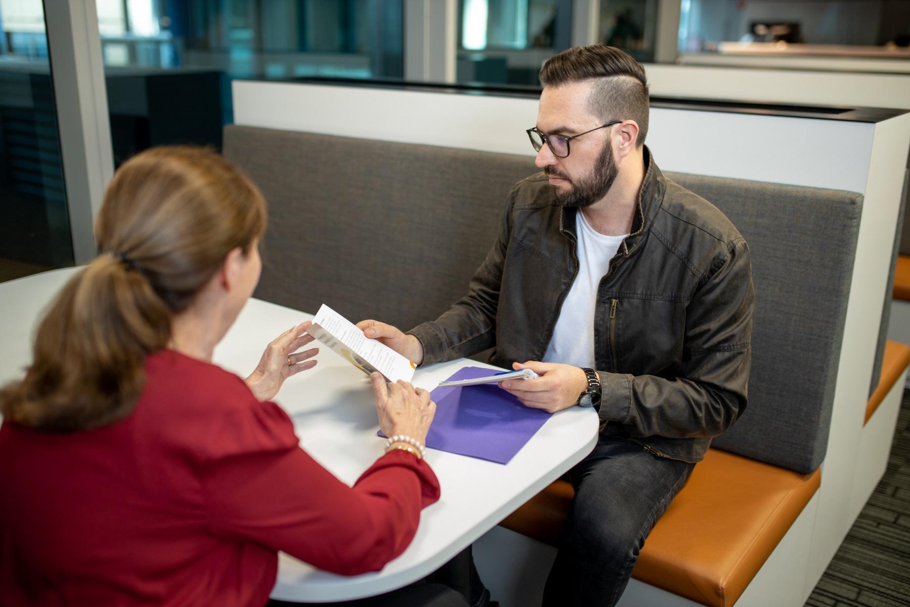 Photo of a man and woman reviewing and discussing documentation.