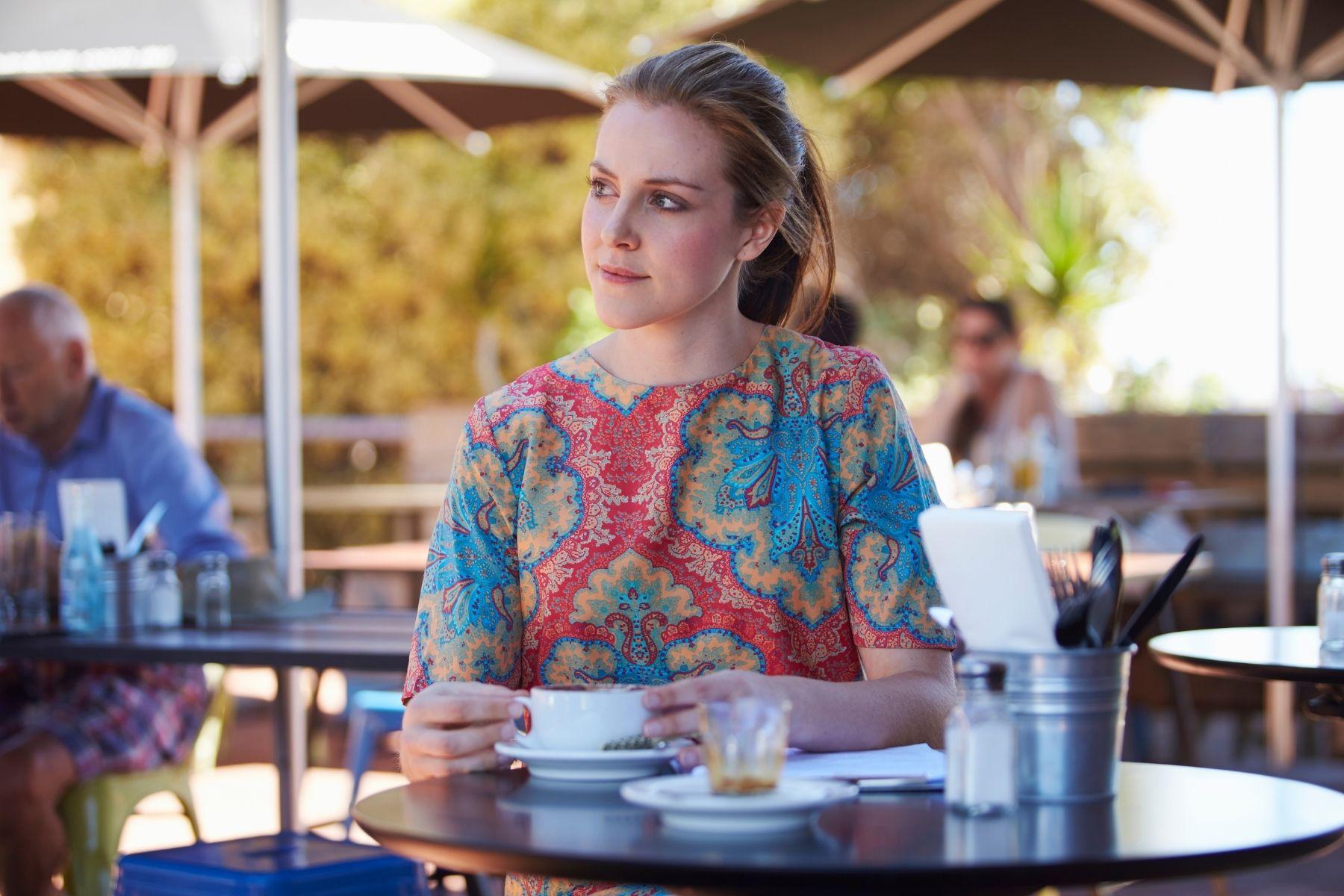 Photo of a woman drinking coffee at a cafe.