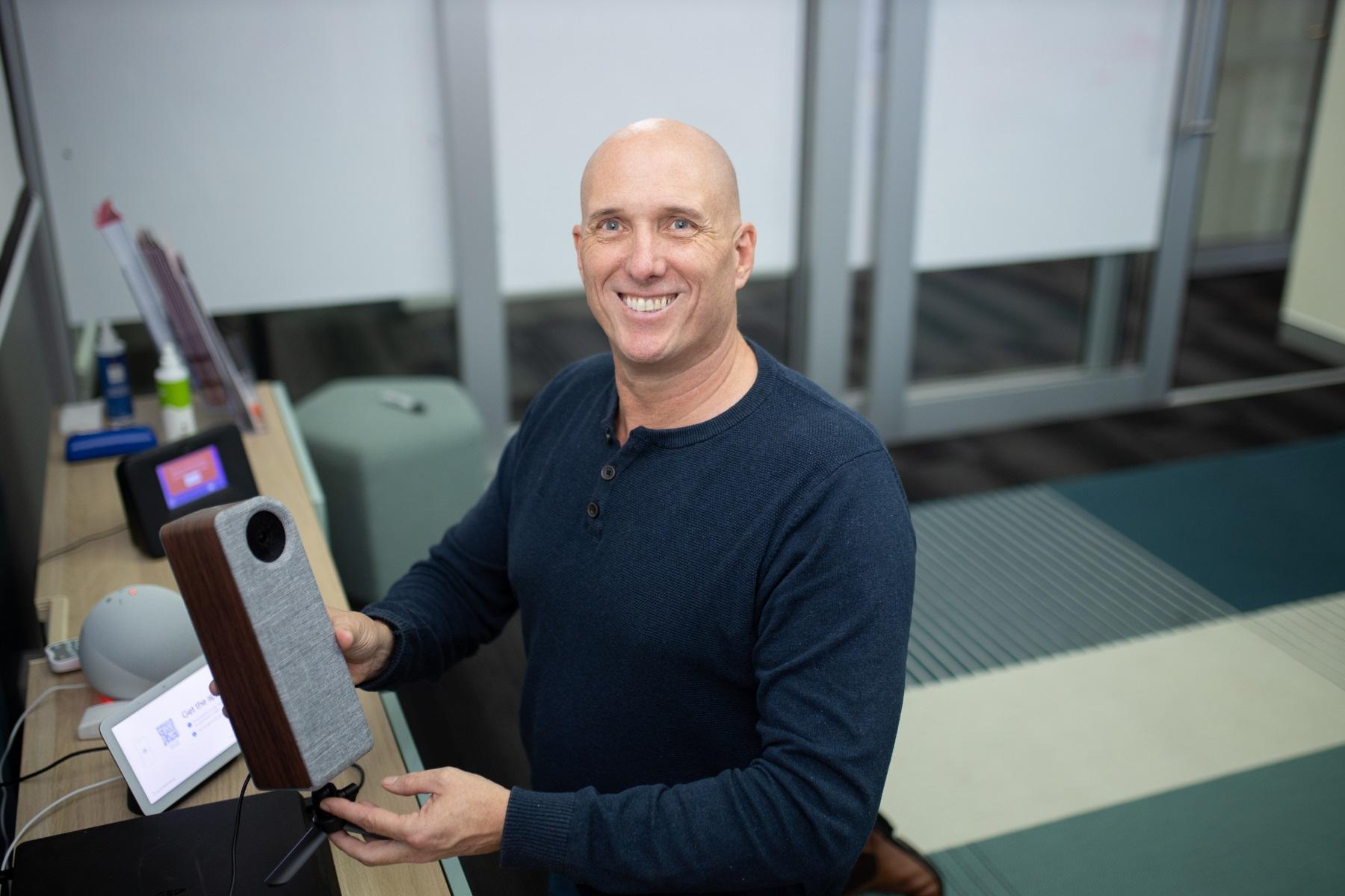Photo of a business owner holding a speaker in a tech store.
