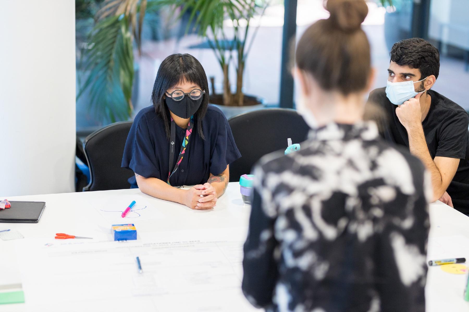 Two women and a man reviewing documentation in a meeting room.